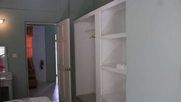 Una camera da letto con un letto, un armadio bianco e un bagno con lavandino e specchio.