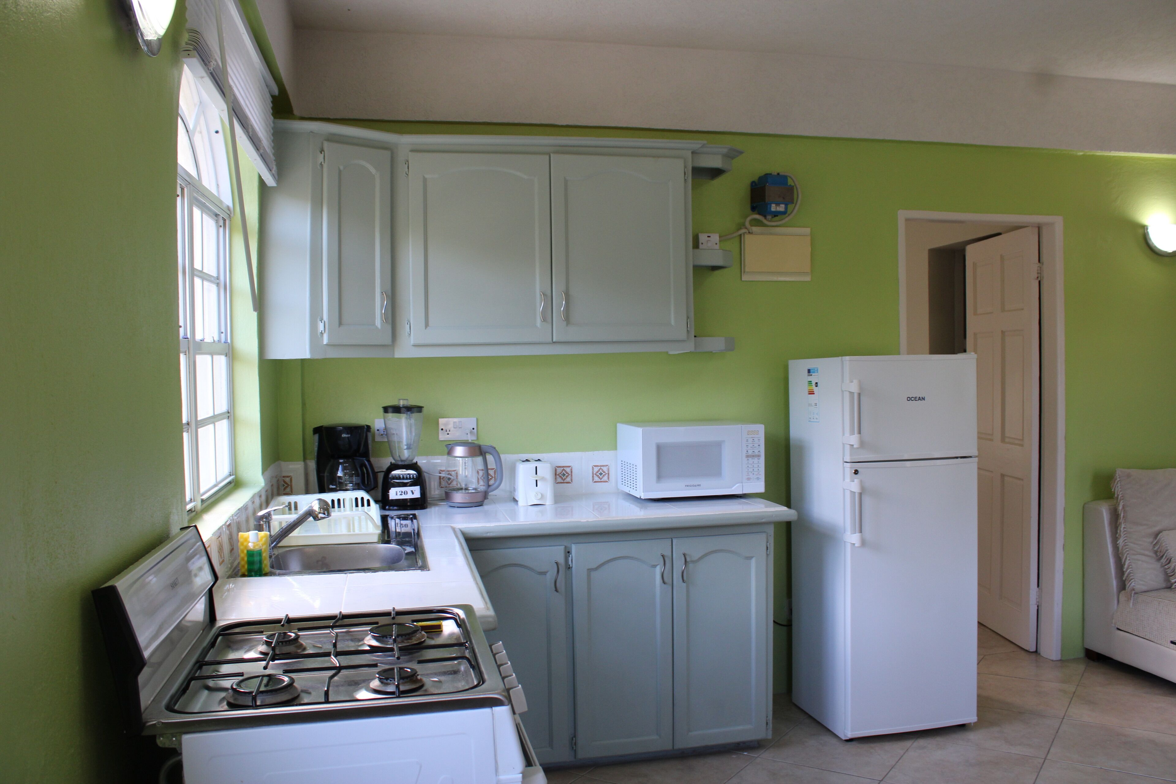 Una cocina con estufa, pileta, armarios, microondas y refrigerador.