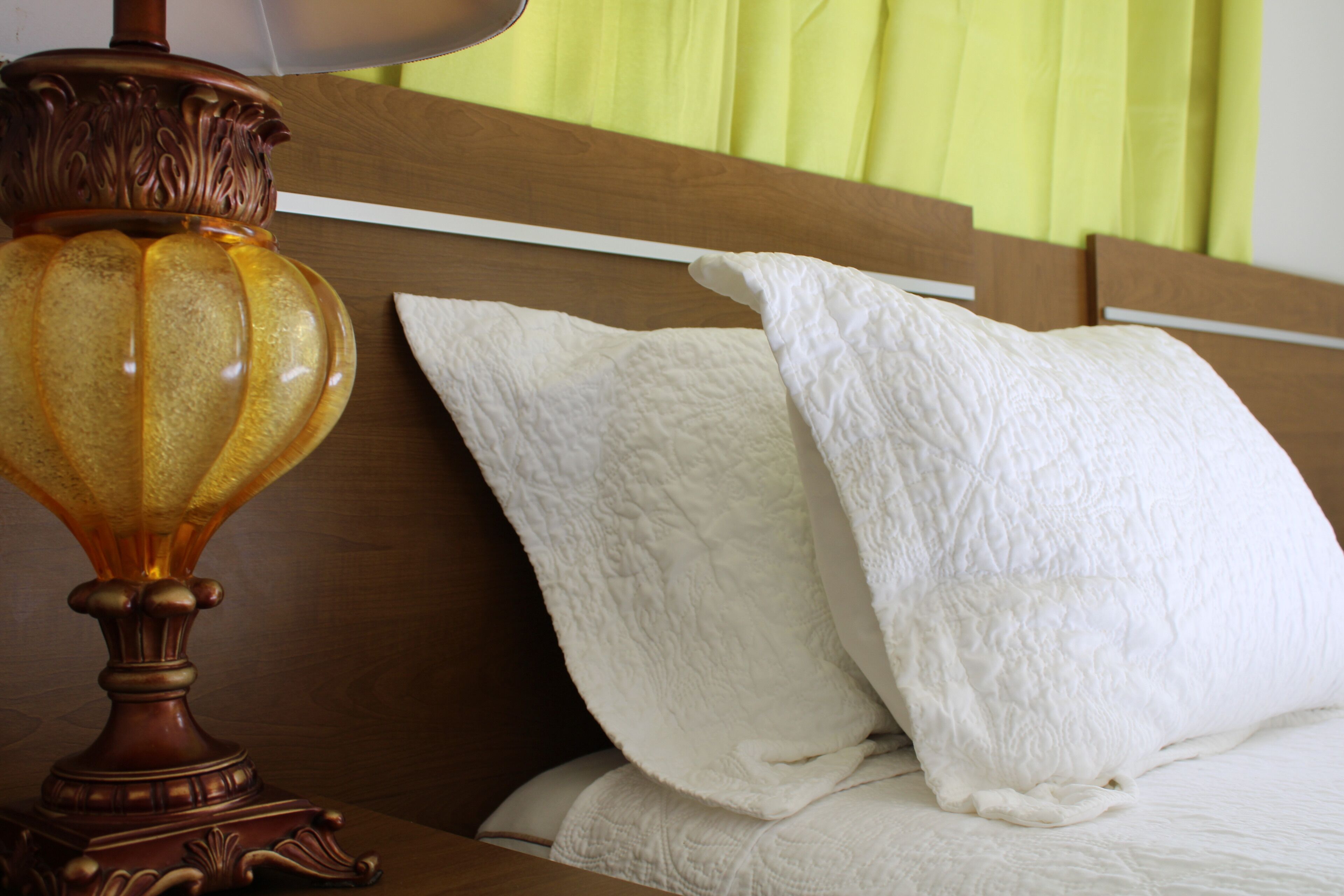 A bed with white pillows and a wooden headboard.