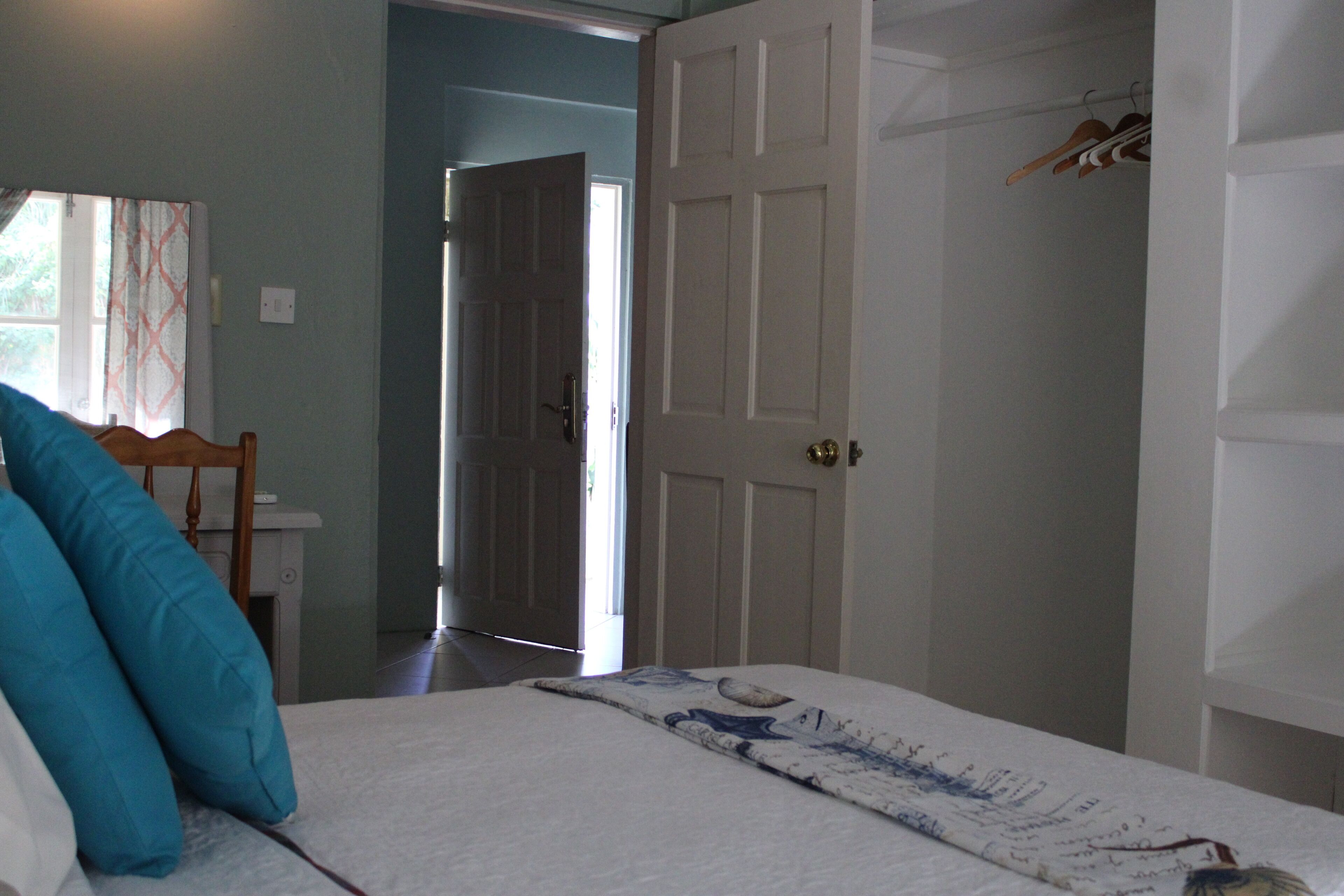 Un dormitorio con cama, una silla y una puerta que da a otra habitación.