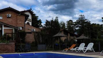 Una piscina al aire libre, sombrillas, sillones reclinables de piscina