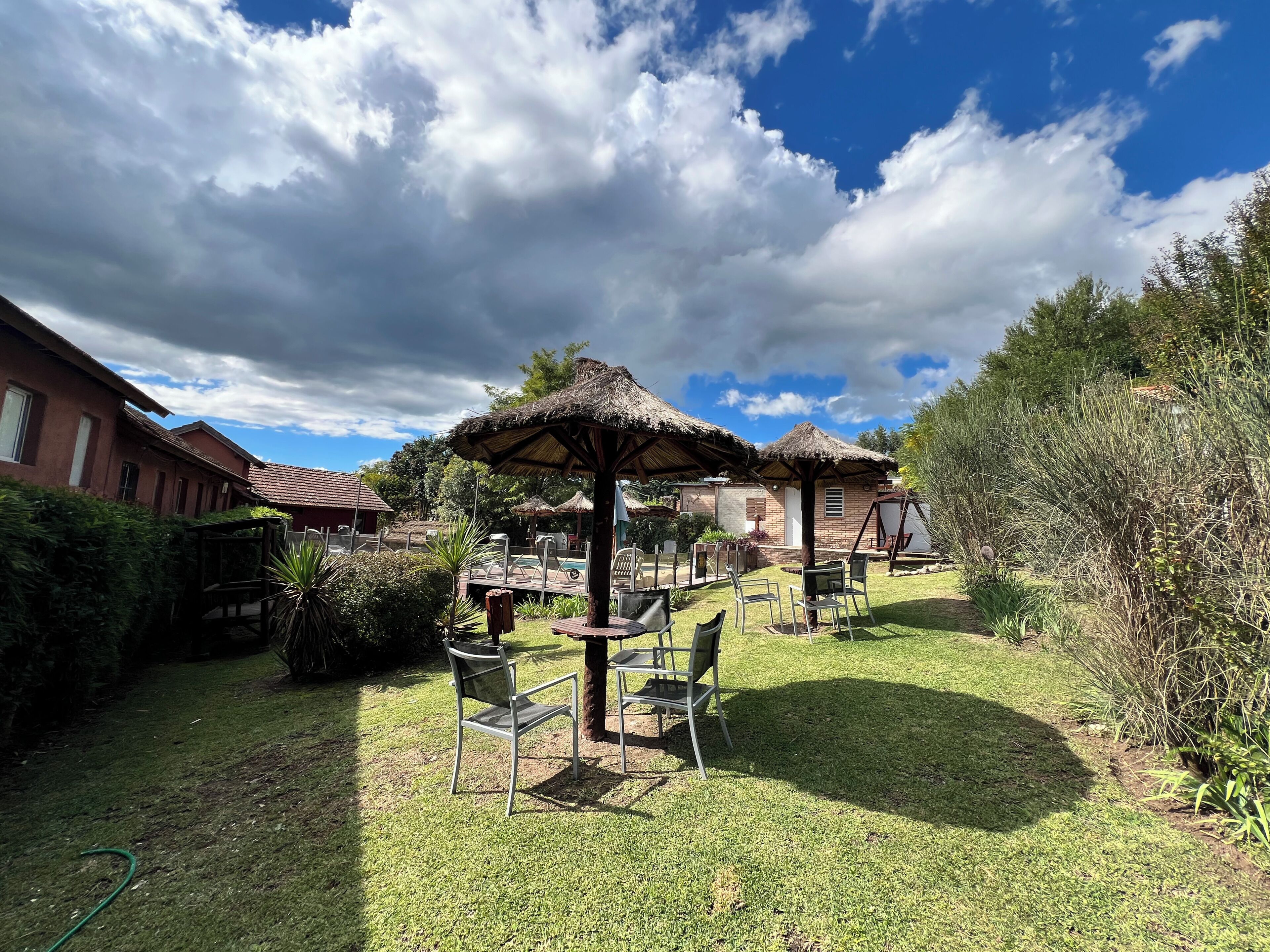 A courtyard with thatched umbrellas, chairs, and a garden.