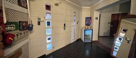 A hotel corridor with a black tiled floor, white brick walls, and a vending machine.