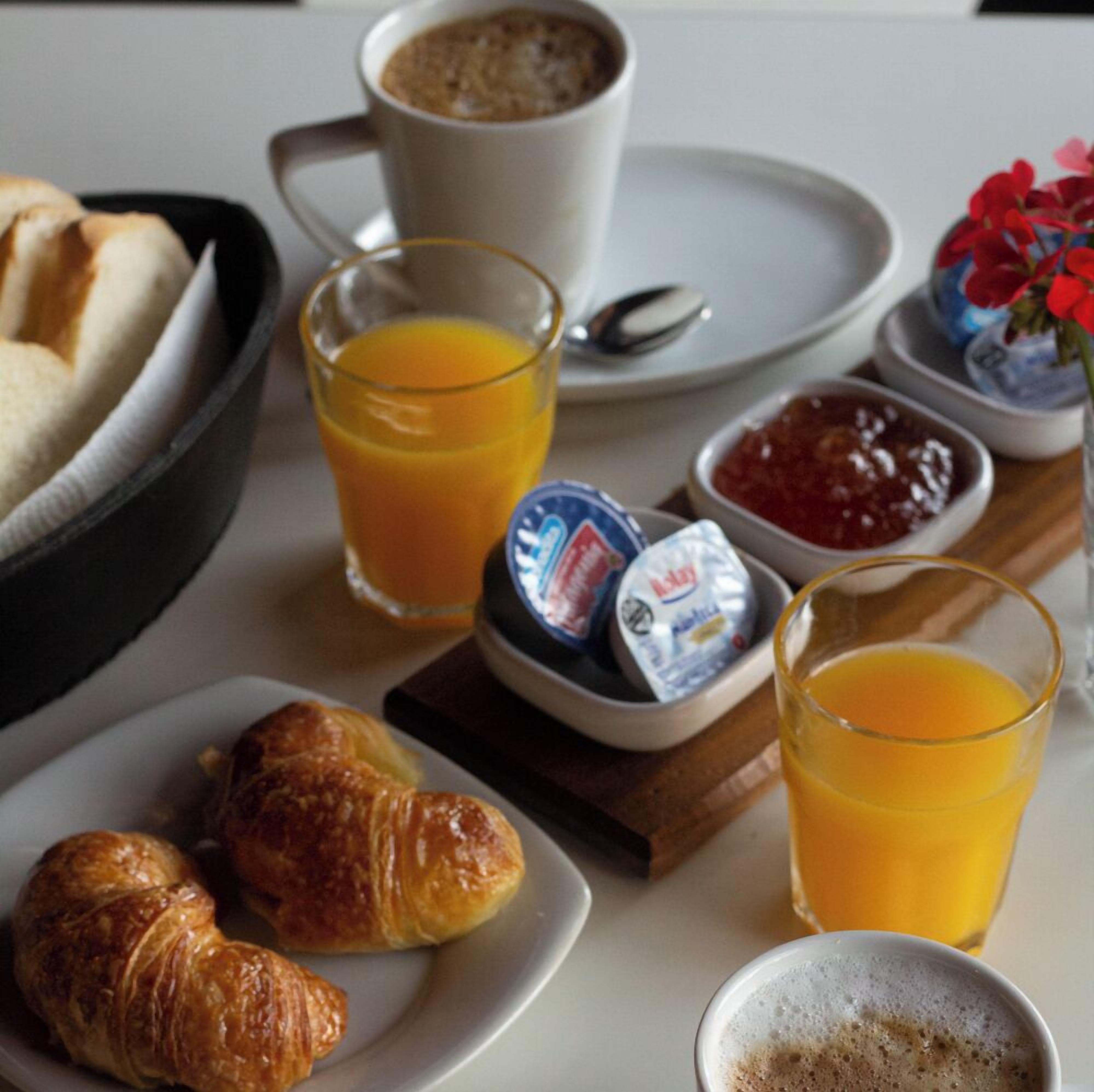 A breakfast setting with croissants, orange juice, coffee, and condiments.