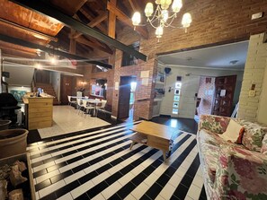 A spacious interior with a black and white tiled floor, wooden furniture, and a brick wall.