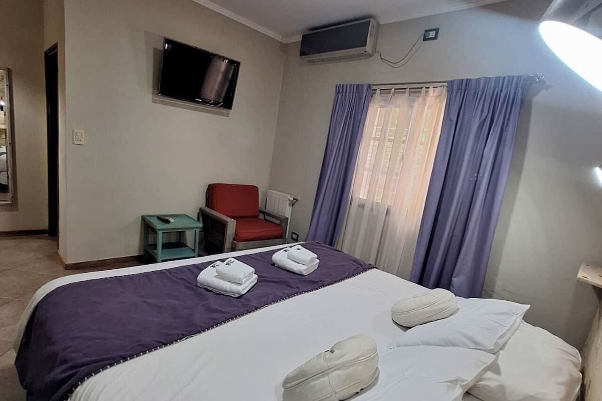 A hotel room with a bed, a television, a chair, and a small table.