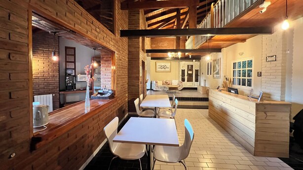 Un restaurante con paredes de ladrillo, vigas de madera, mesas y sillas blancas.