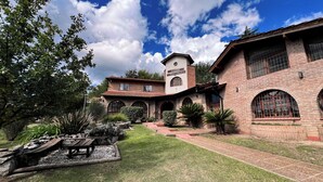 Un edificio de ladrillo tradicional con una torre, ventanas de arco y un jardín bien cuidado con un patio.