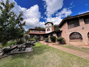 A traditional brick building with a tower, arched windows, and a well-maintained garden with a patio area.