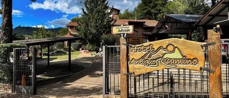 Un letrero de madera con la inscripción 'Hotel Antiguos Camino' y una reja metálica.