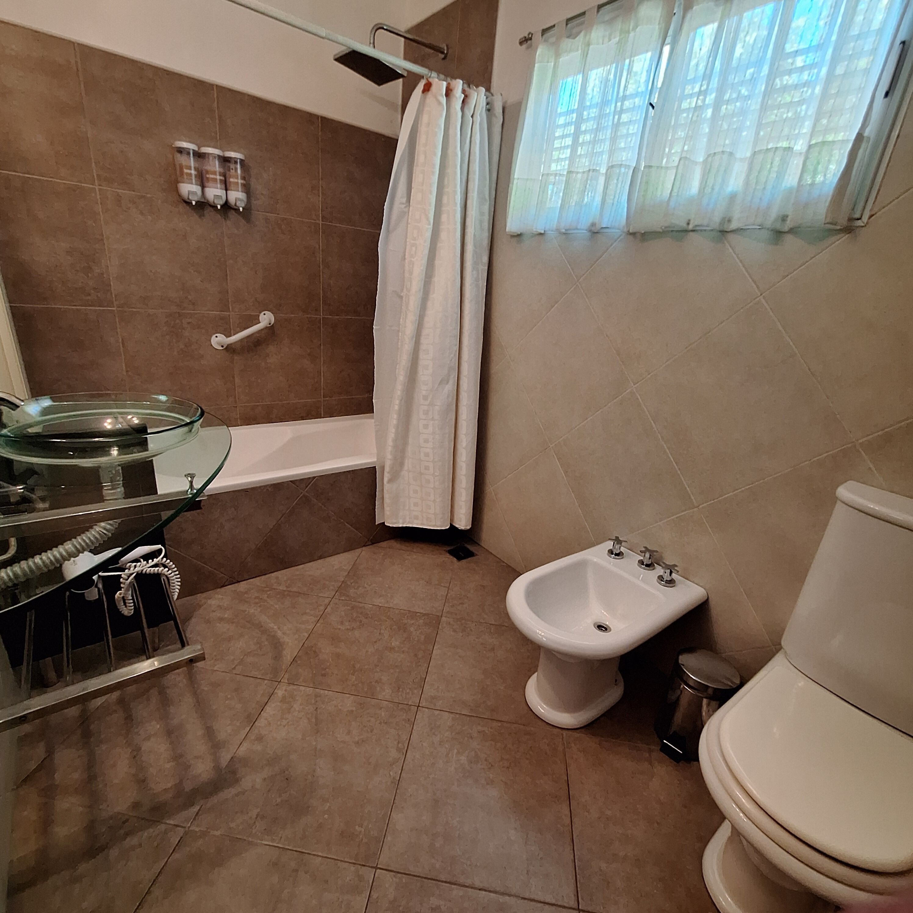 A bathroom with a glass shower enclosure, a bidet, and a toilet.