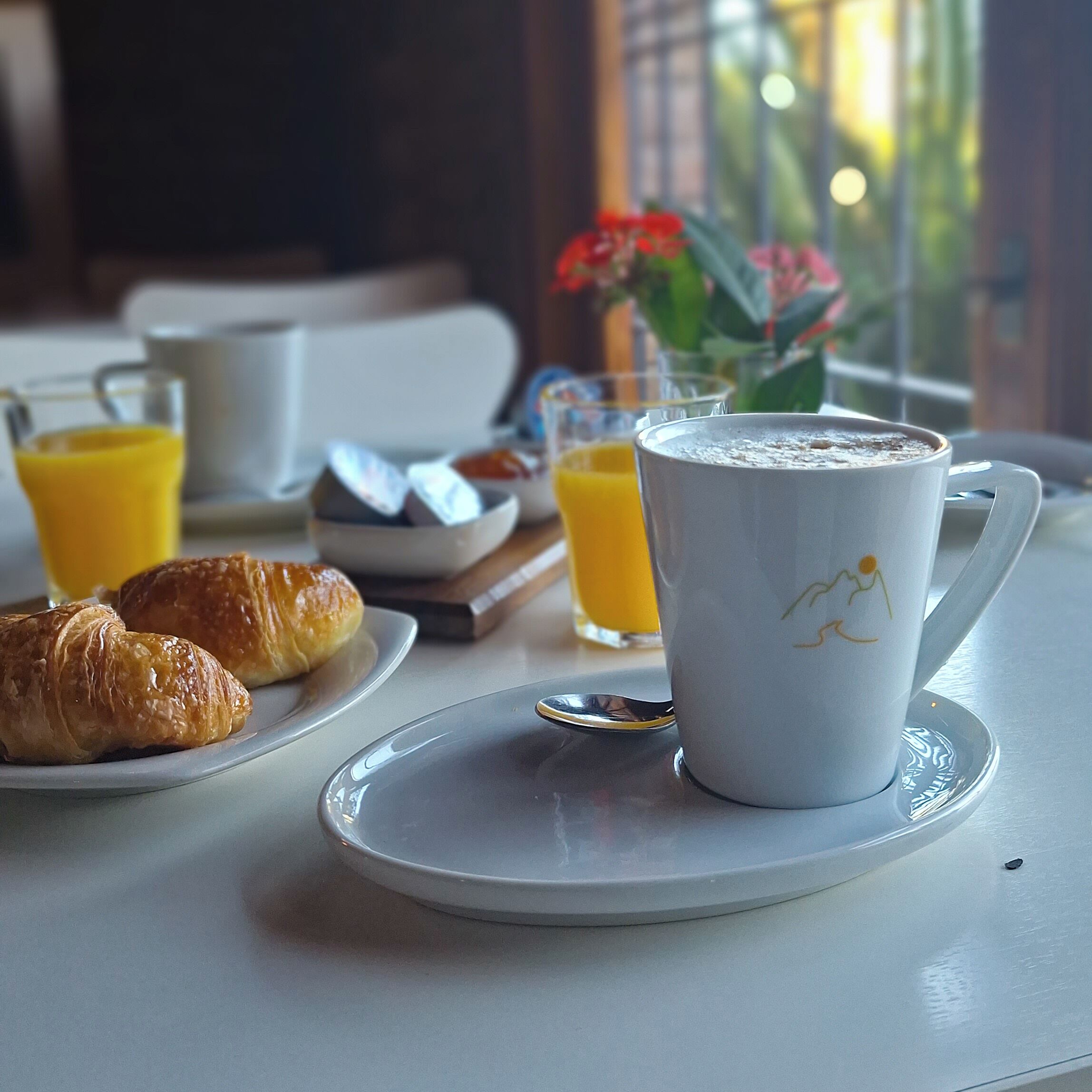 A breakfast setting with croissants, coffee, and orange juice on a table.