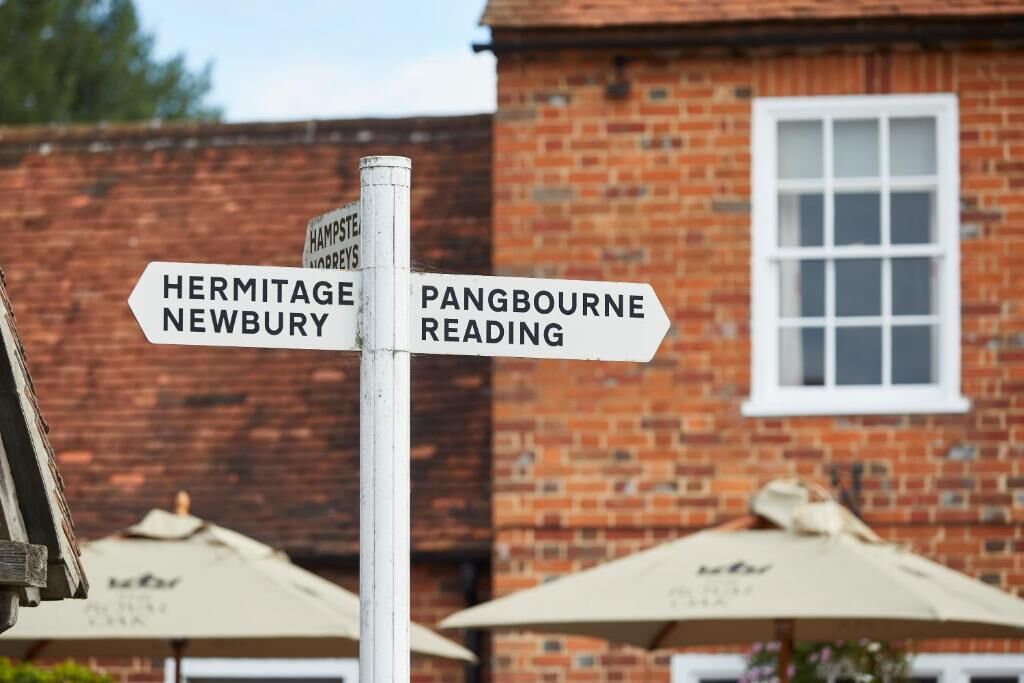 A directional signpost with arrows pointing towards Hermitage, Newbury, Pangbourne, and Reading.