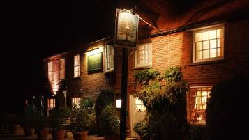 A brick building with a pub sign, windows, and potted plants.
