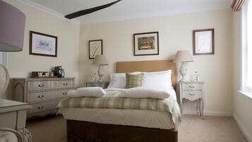 A neatly arranged bedroom with a bed, bedside tables, a dresser, and framed pictures on the wall.