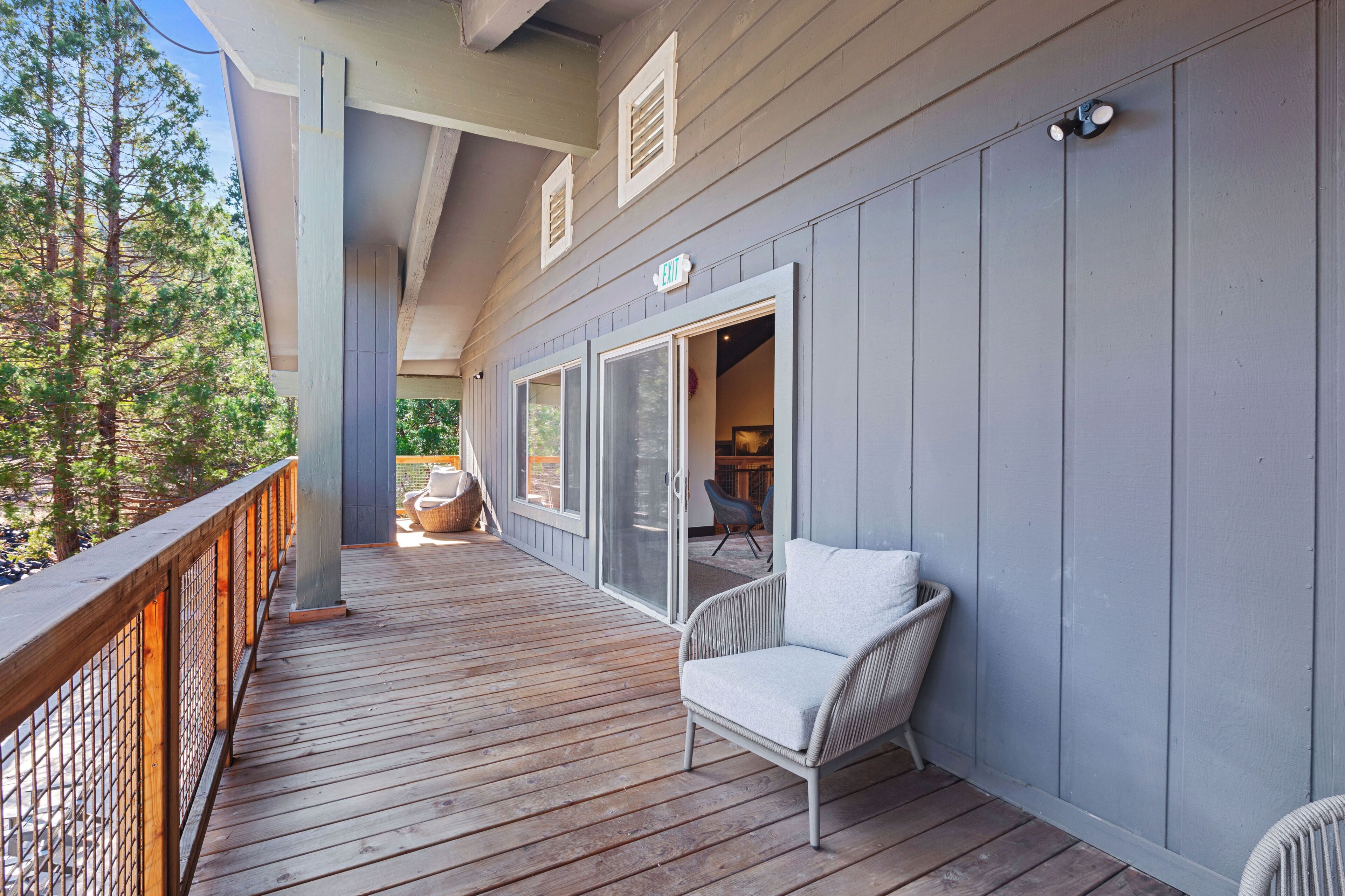 A wooden deck with a railing, a white chair, and a sliding glass door leading to an interior space.