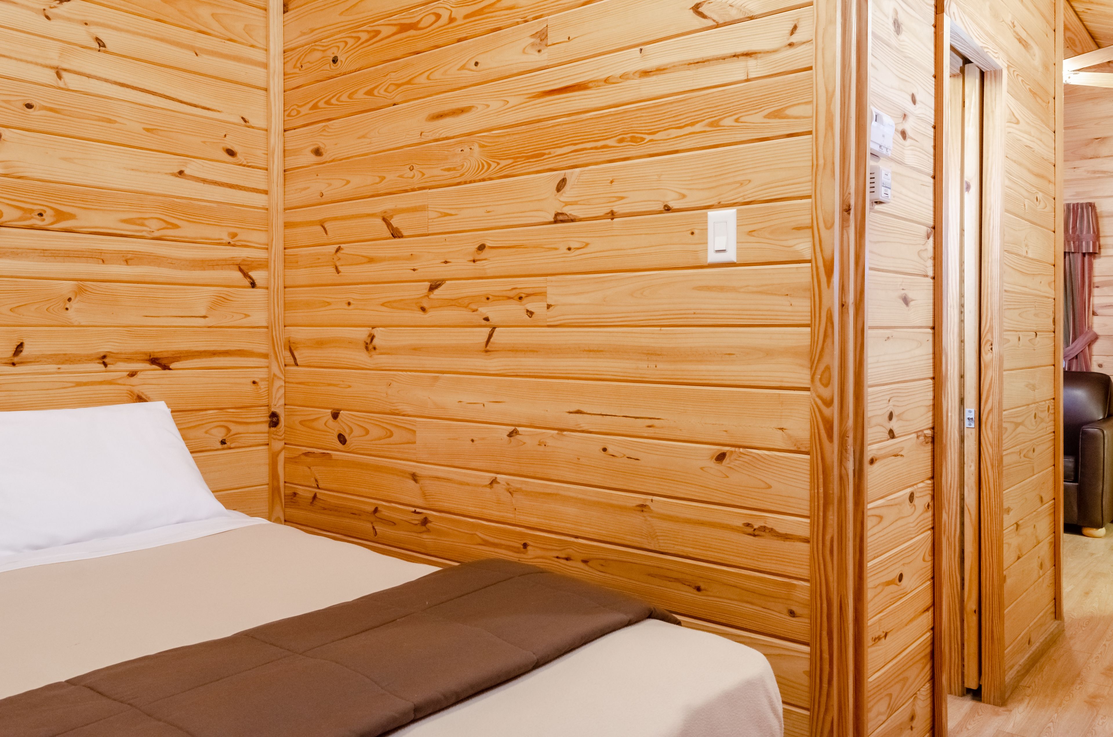 Una habitación con paneles de madera, una cama, una puerta y un banco.