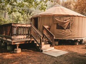 A yurt with a wooden deck and a ramp leading to the entrance.