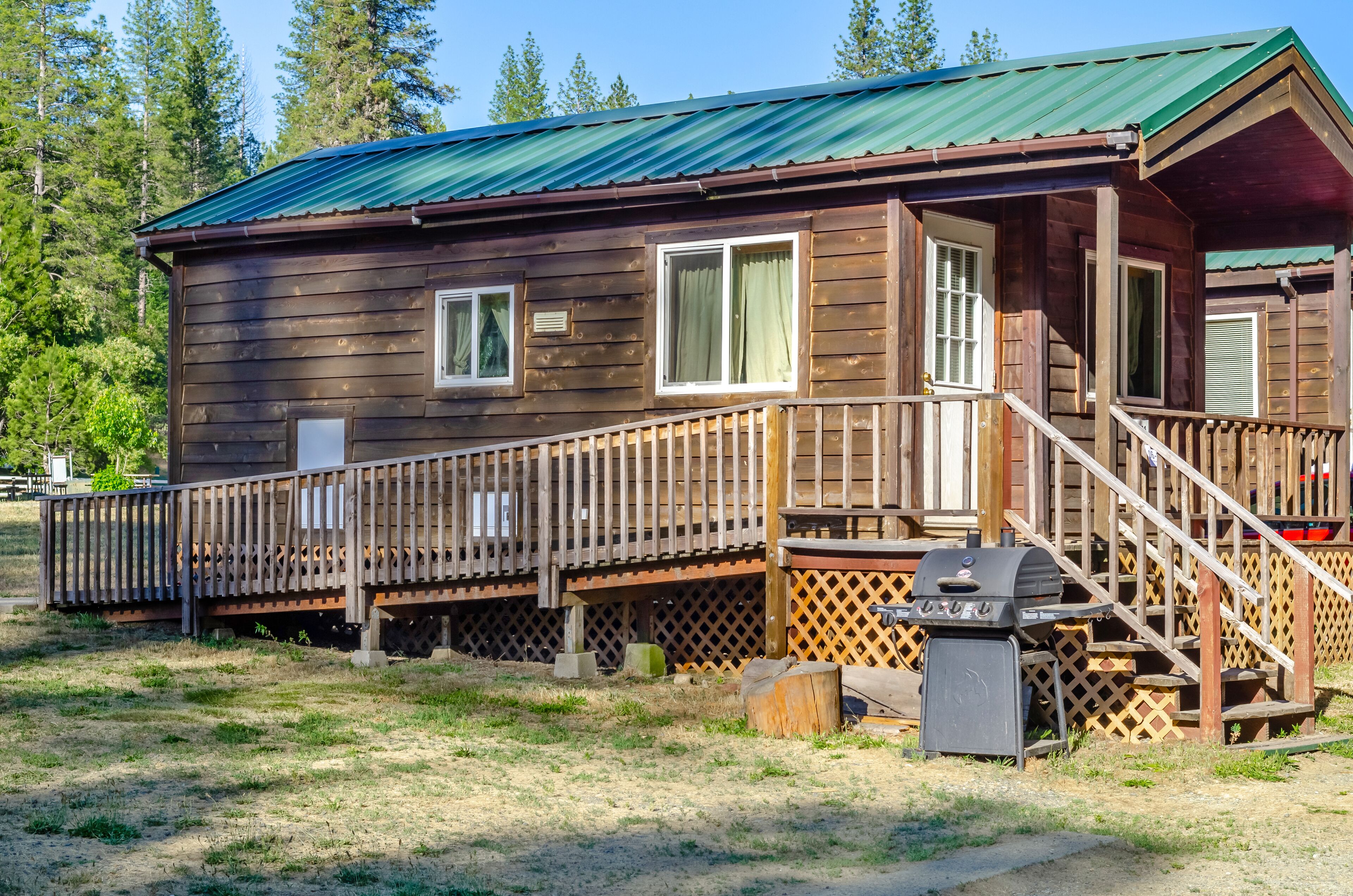 A wooden cabin with a porch and a grill.