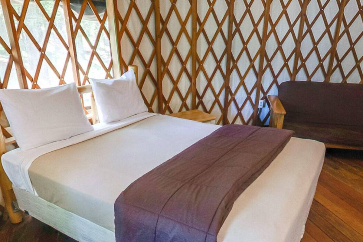 A room with a bed, a sofa, and a wooden lattice partition.