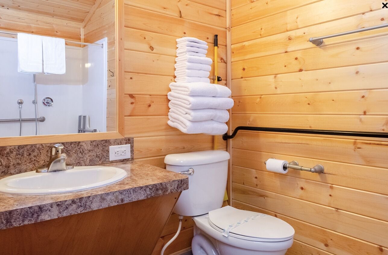 Een badkamer met houten inrichting, een wastafel, toilet en een handdoekhouder.