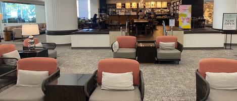 Un café Starbucks situé dans un hall moderne, doté d’espaces pour s’asseoir et d’un comptoir bien visible.