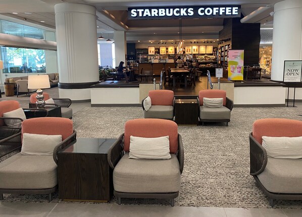 Una cafetería Starbucks en un vestíbulo moderno con zonas de estar y una barra visible.