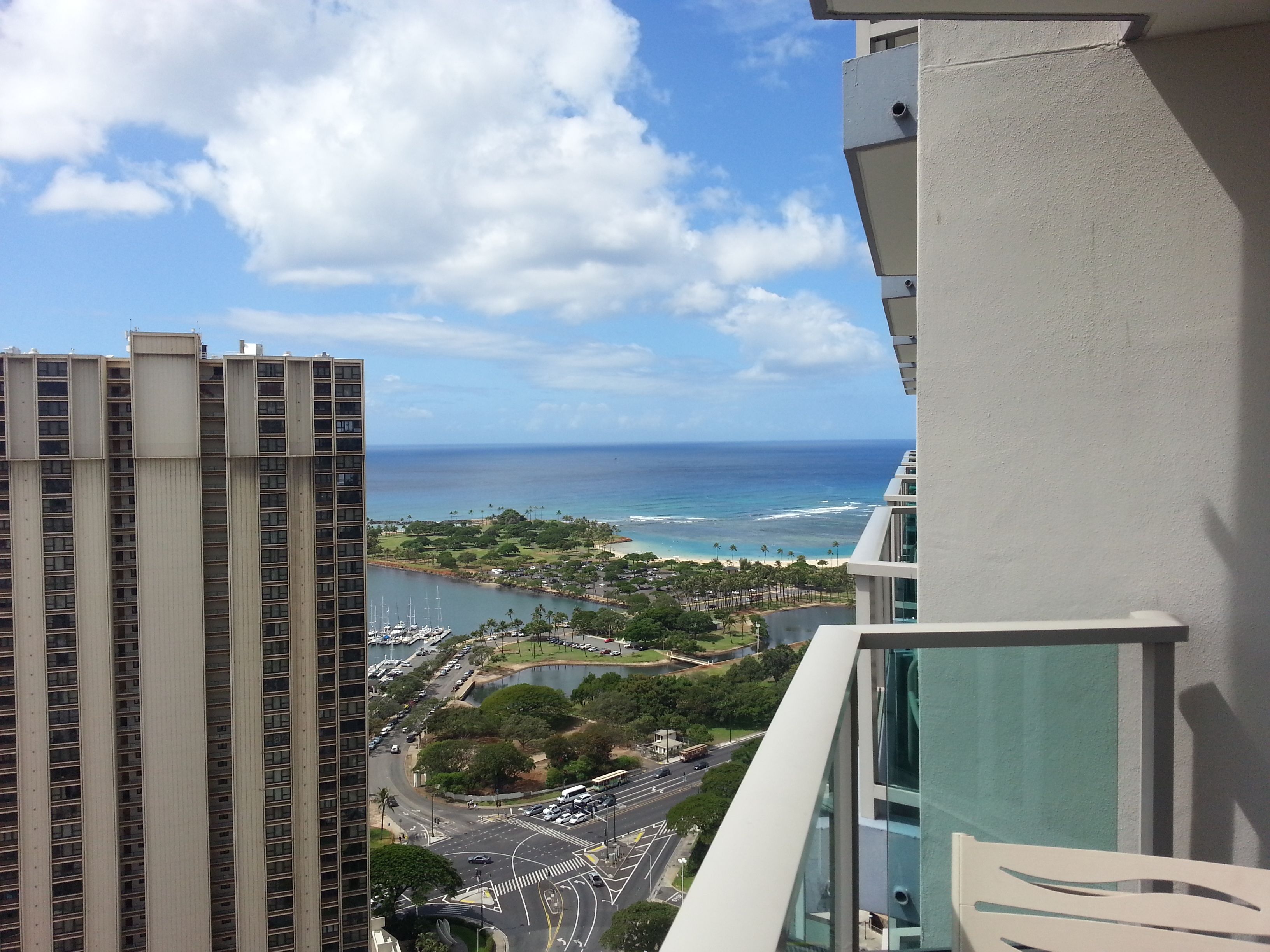 A high-rise building with a view of a coastal area, including a beach and a marina.