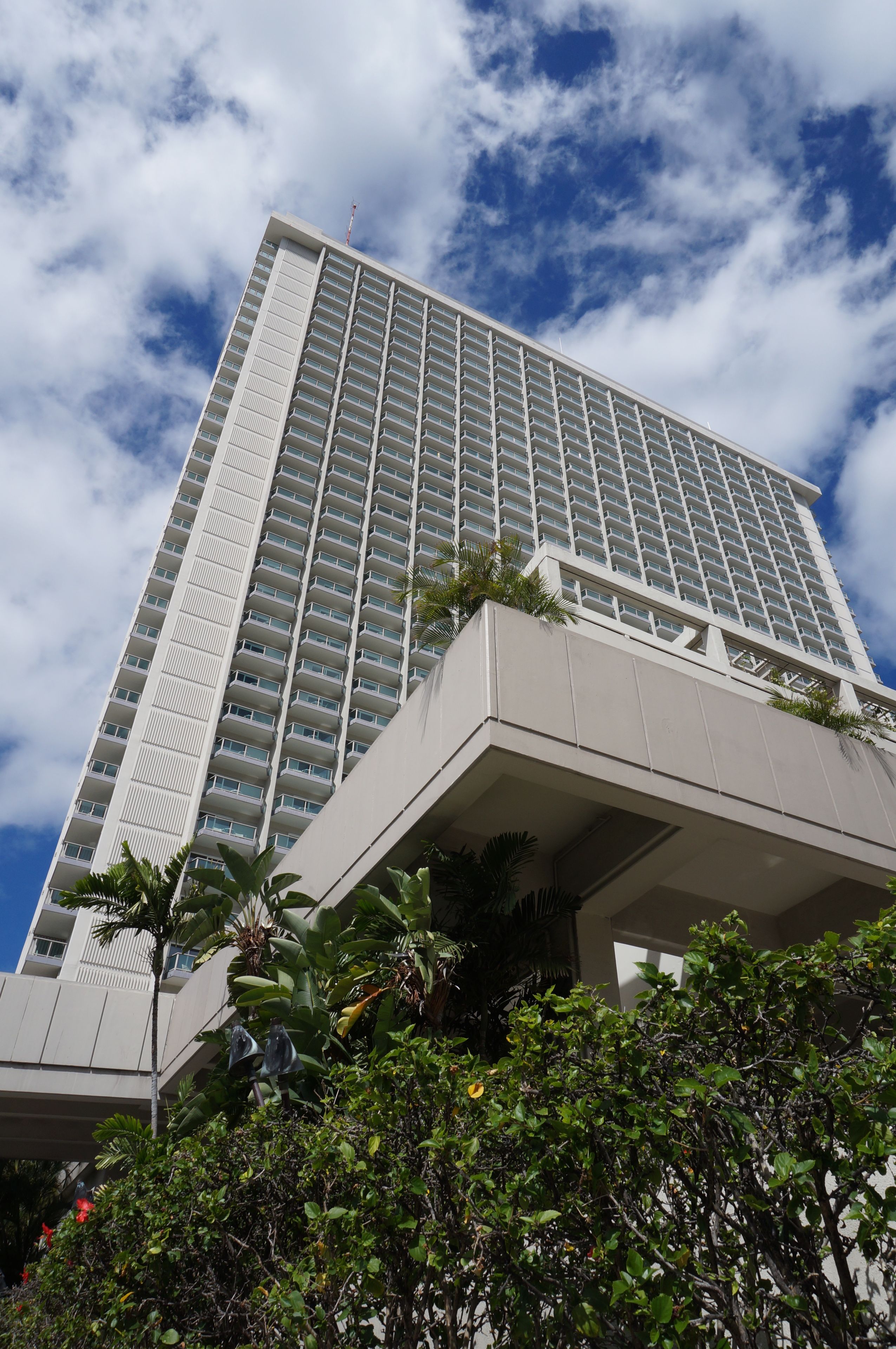 A tall, modern hotel building with a prominent central tower and multiple balconies.