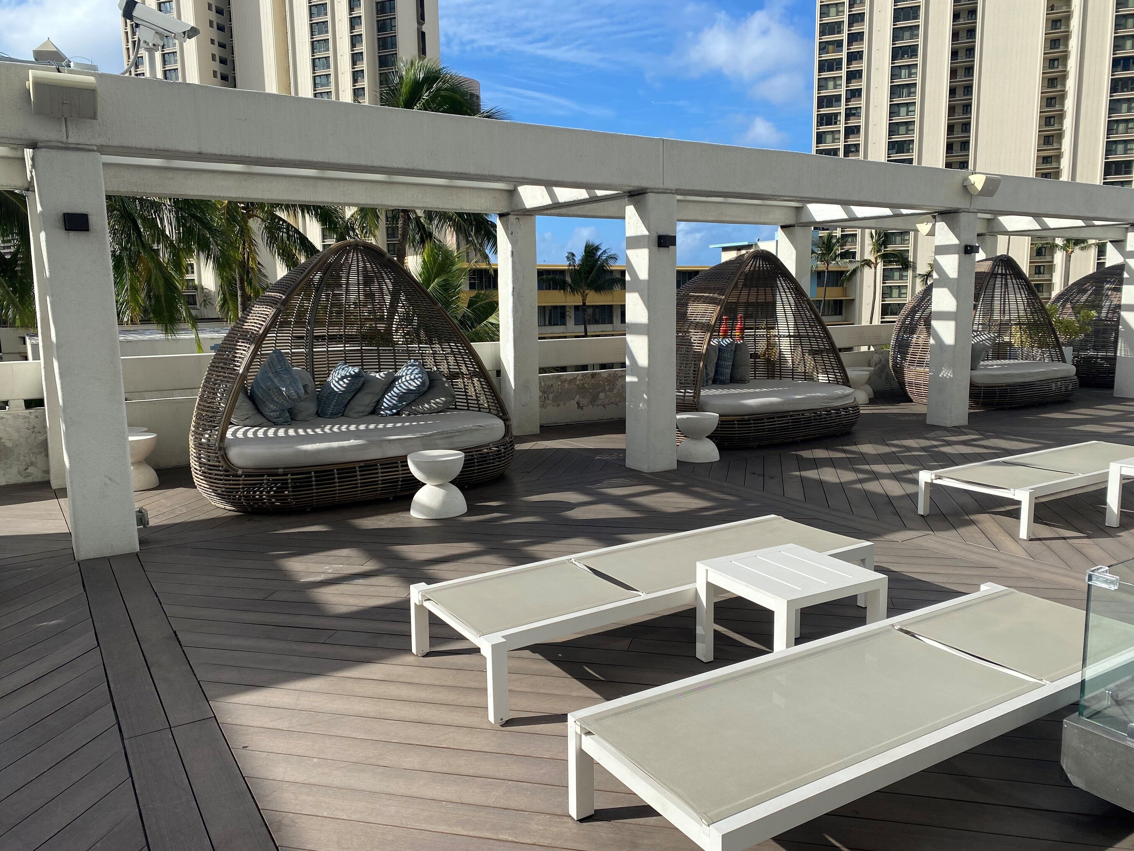 A rooftop lounge area with wicker seating and sun loungers.