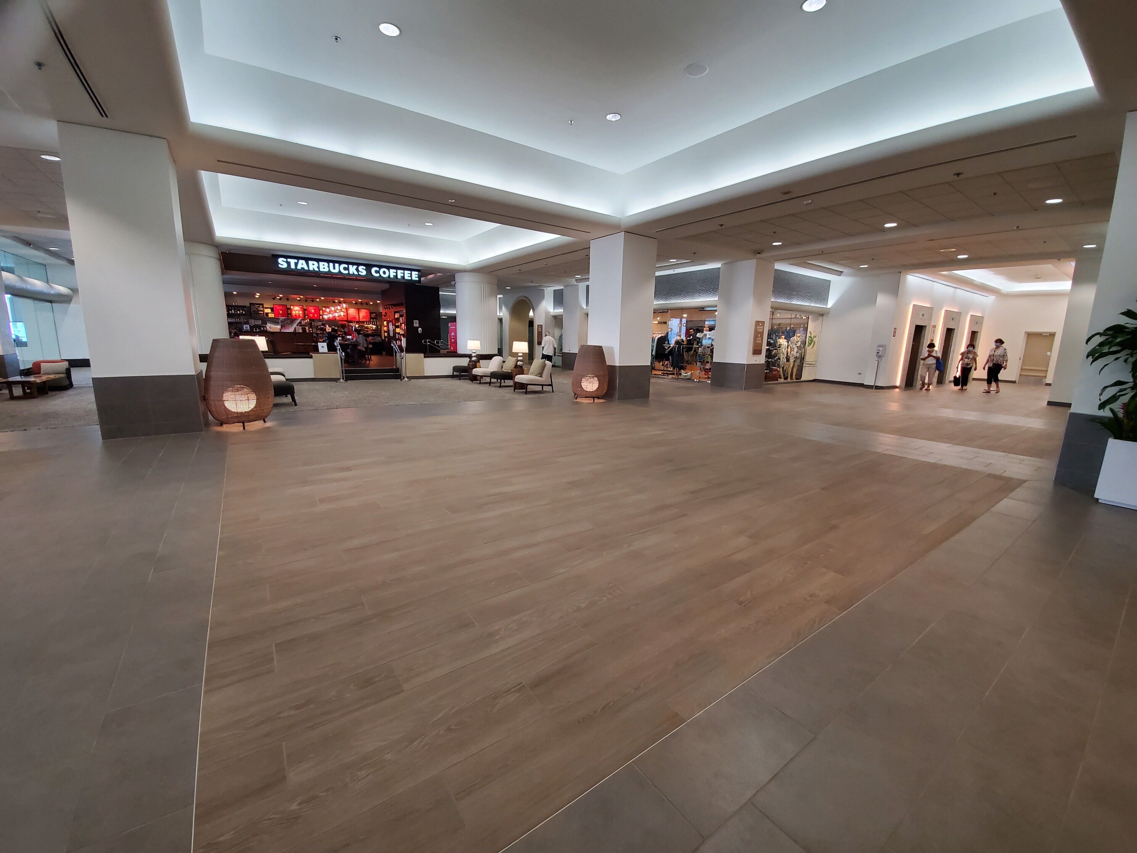 A spacious indoor area with a Starbucks Coffee, seating arrangements, and a modern architectural design.