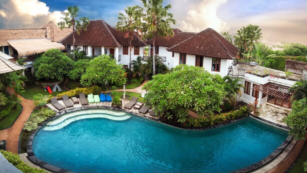 A resort with a swimming pool, lounge chairs, and tropical landscaping. - Ecosfera Hotel (Canggu)