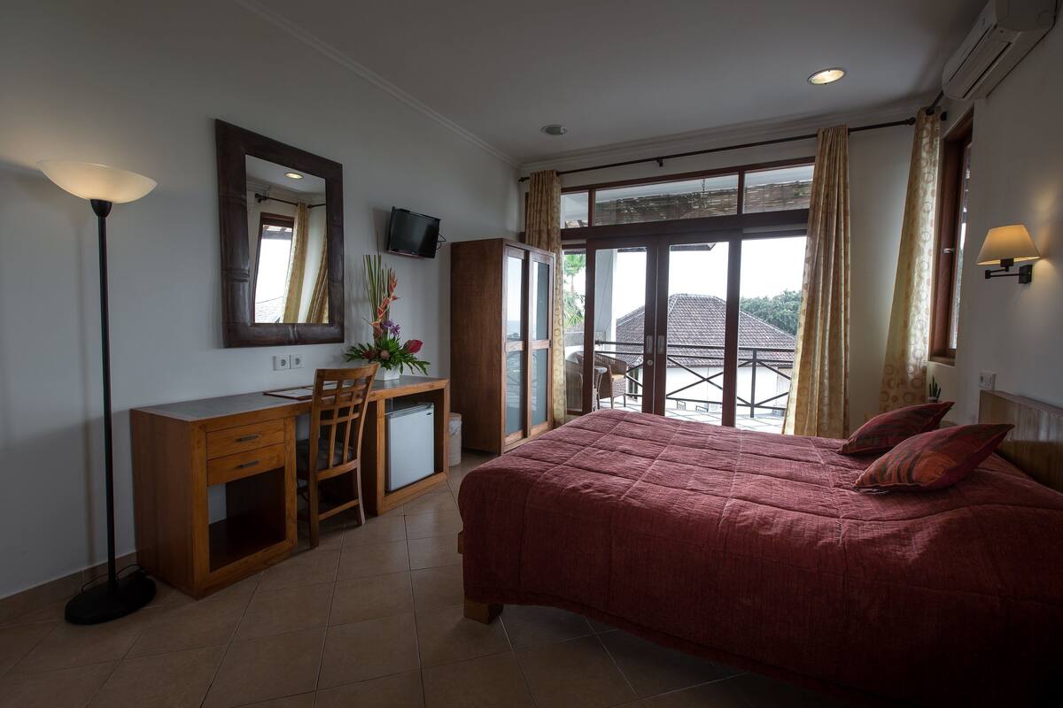 A bedroom with a bed, desk, chair, and a TV.