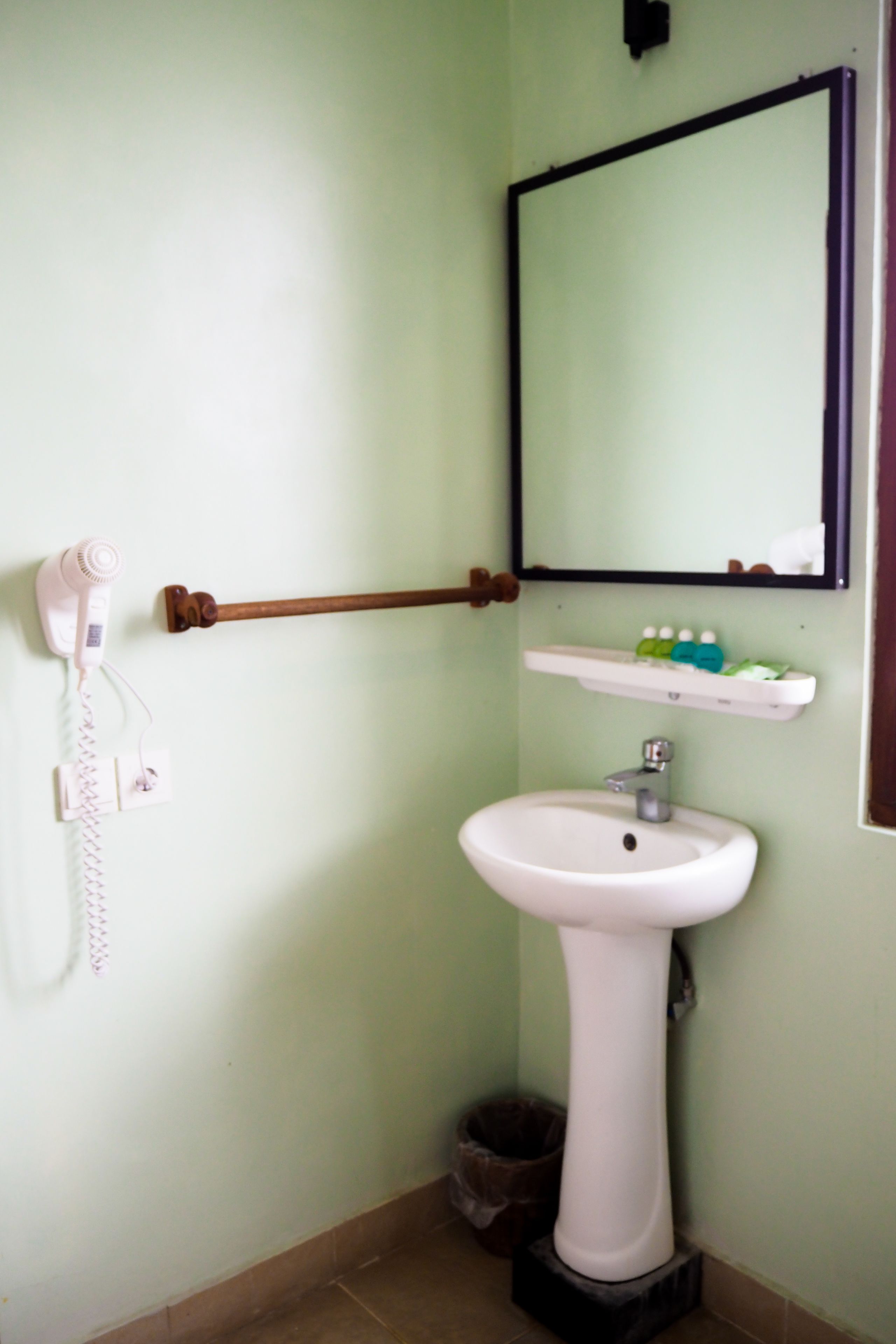 A bathroom with a white sink, a mirror, a towel rack, and a hairdryer.
