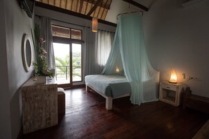 Un dormitorio con cama, mesita de noche, cortinas en la ventana y vistas al exterior.