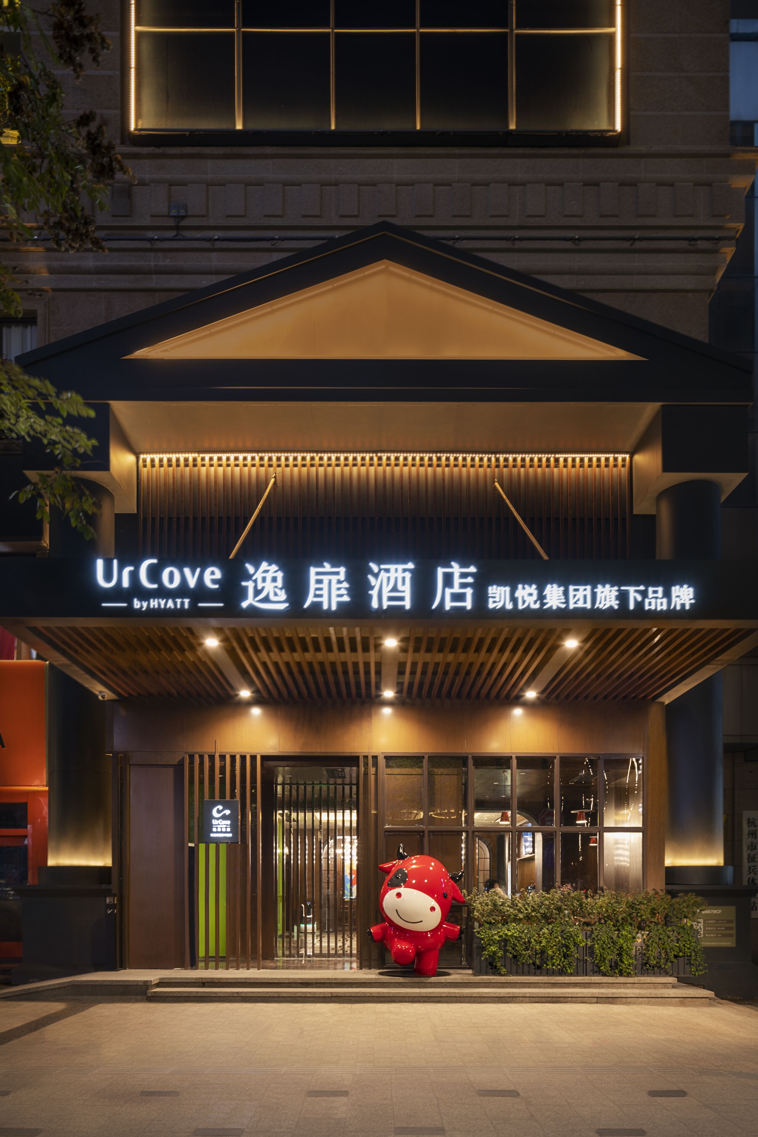 A hotel entrance with a sign reading "UrCove by HYATT" and a large red mascot outside.