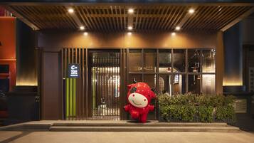 A hotel entrance with a sign reading "UrCove by HYATT" and a large red mascot outside.