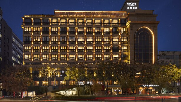 A multi-story hotel with a prominent arched entrance and numerous illuminated windows.