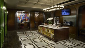 A lobby with a reception desk, a large chandelier, a television screen, and a patterned floor.