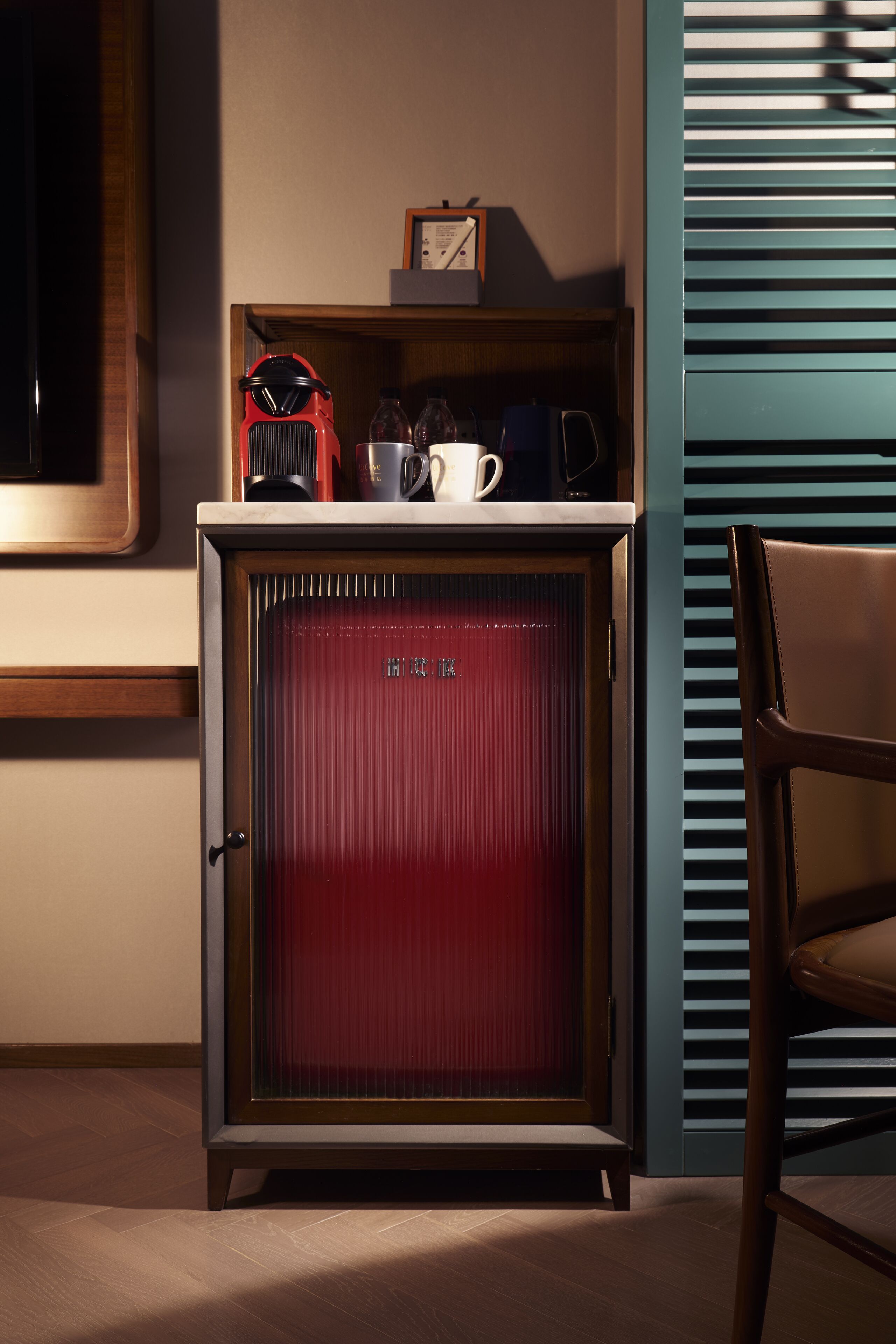 Un refrigerador rojo con un marco de madera, una cafetera, una taza y un reloj encima.