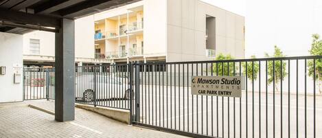A gated entrance to a building with a sign for 'Mawson Studio Apartments' and a car park entry.