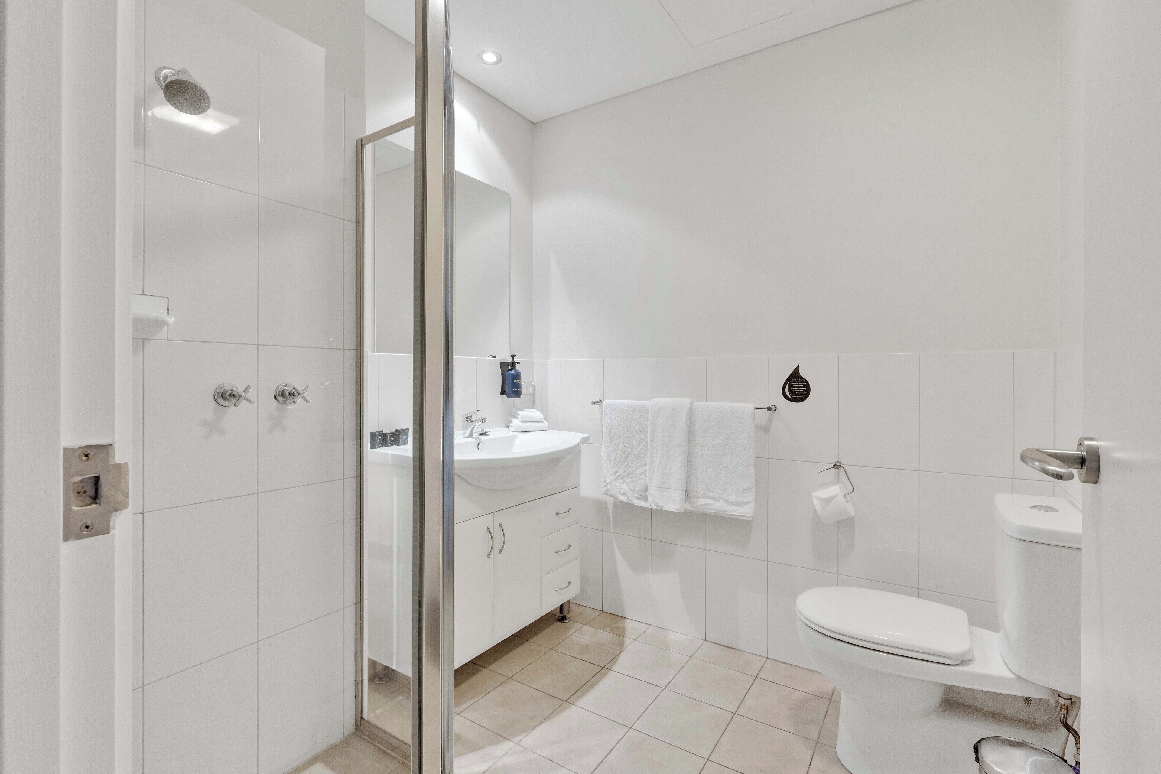A modern bathroom with a glass shower enclosure, a white sink, and a toilet.