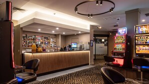 A bar area with a counter, seating, and slot machines. - Mawson Lakes Hotel & Function Centre (Mawson Lakes)