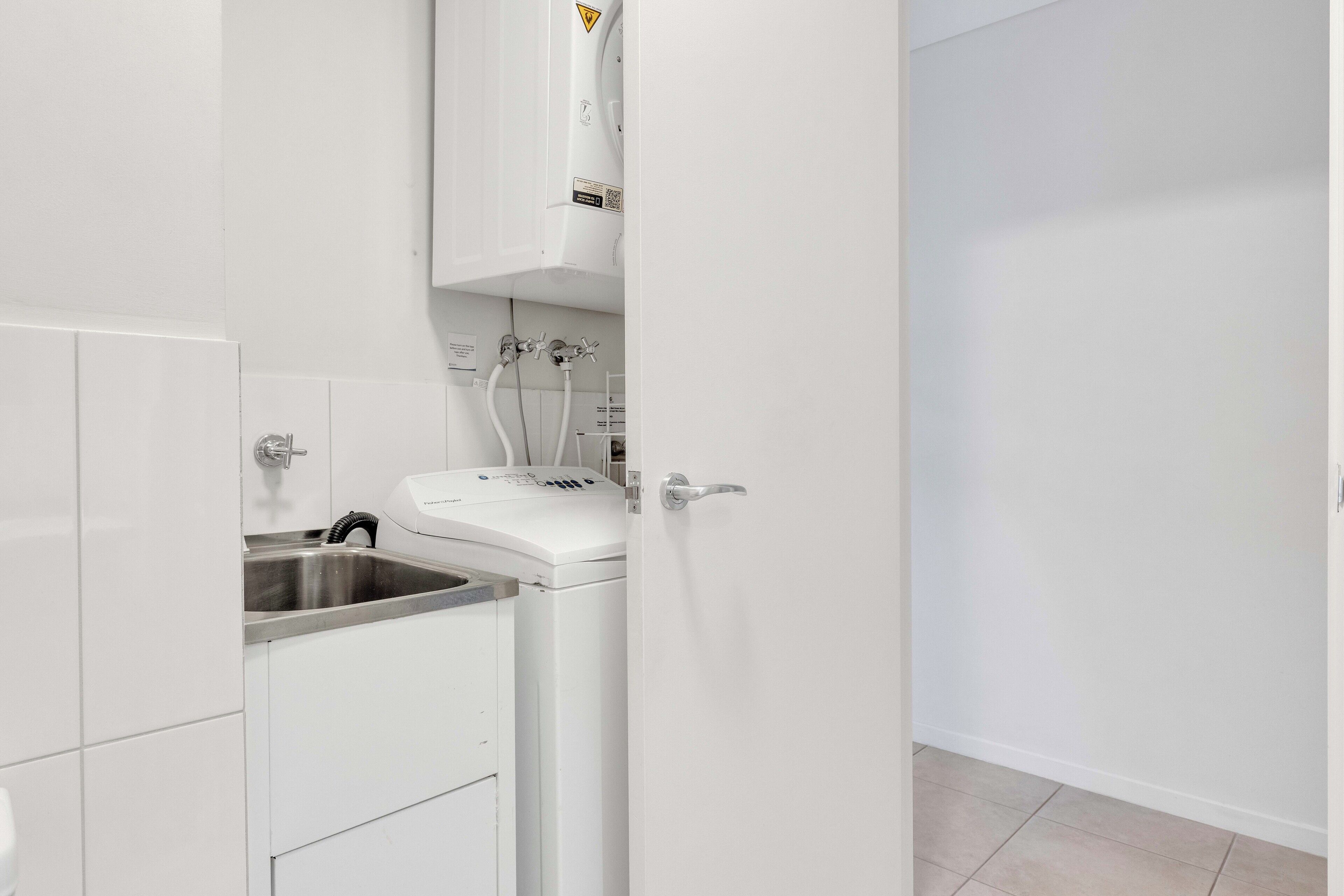 A modern kitchen with white cabinets, a built-in dishwasher, and a water heater.