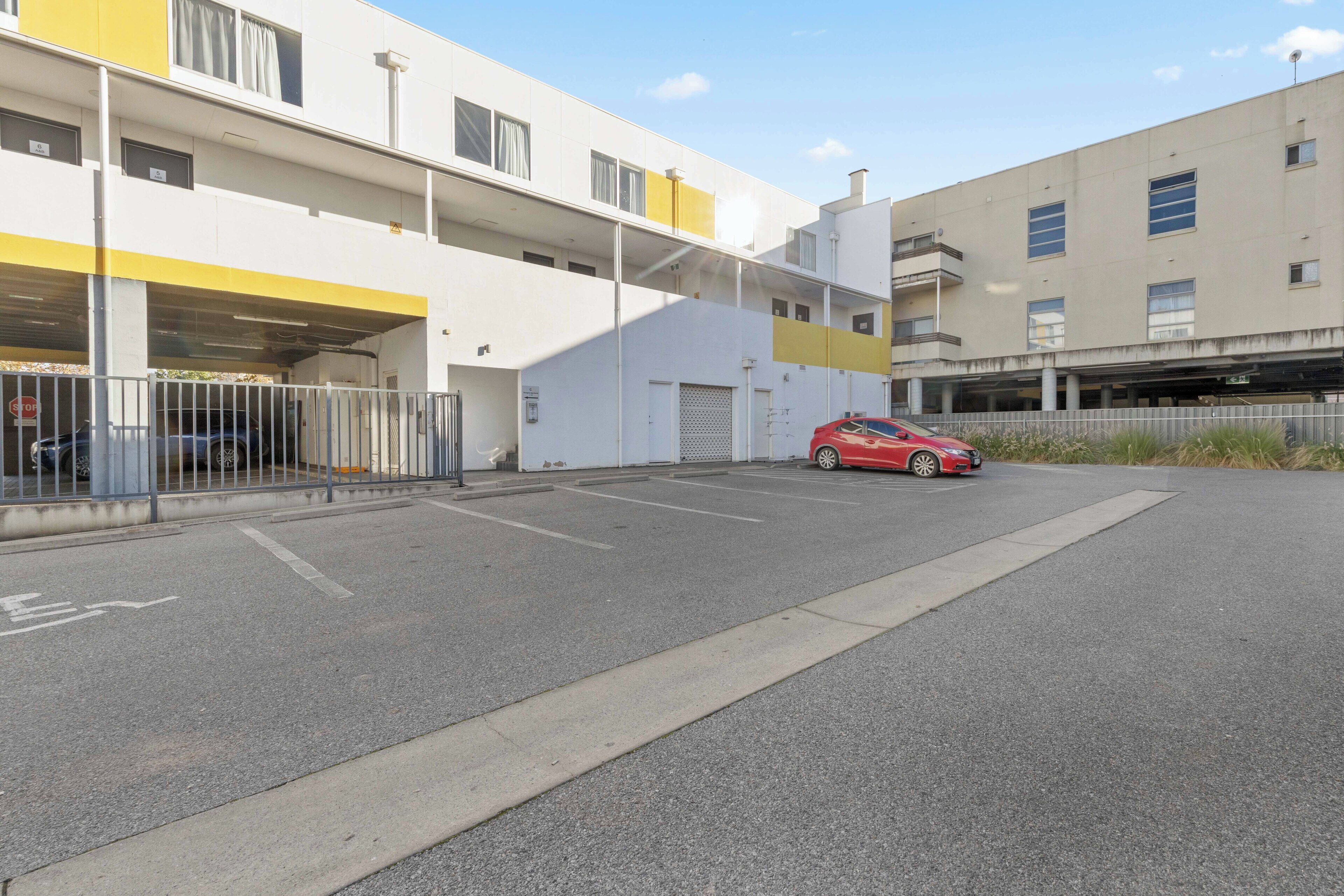 Um estacionamento de vários andares com um carro vermelho estacionado dentro.