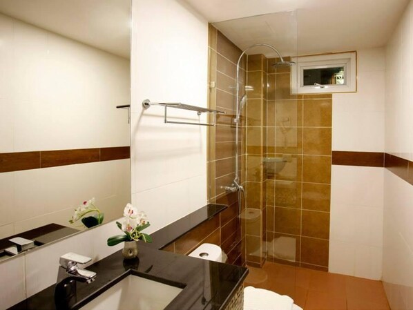 A modern bathroom with a glass-enclosed shower, a vanity with a mirror, and a small window above the shower. - Orchid Resortel (Patong)