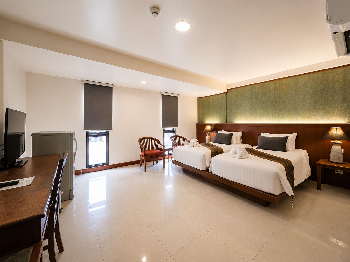 Ein Hotelzimmer mit zwei Betten, einem Schreibtisch mit Computer und einem Stuhl.