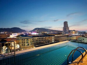 Une piscine sur le toit offrant une vue sur le paysage urbain au crépuscule.