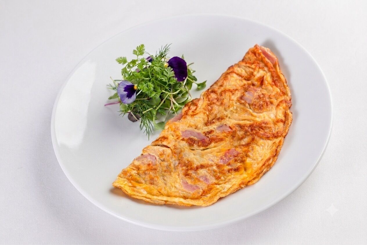 A single omelette on a white plate with a side of greens.