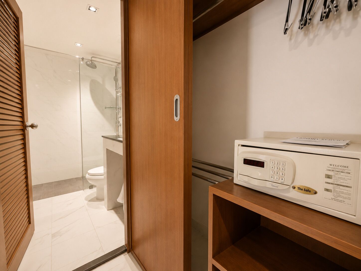 Hotelkamer met een houten deur, een digitale safe en uitzicht op de badkamer.